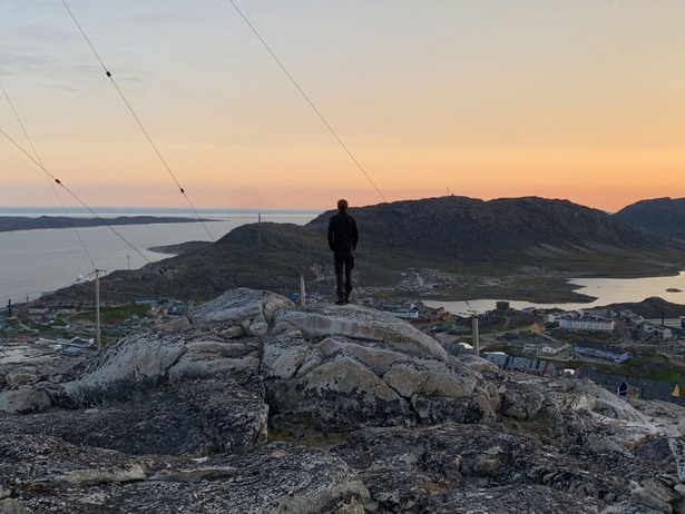 Magne standing atop a hill looking at the sunset in Greenland
